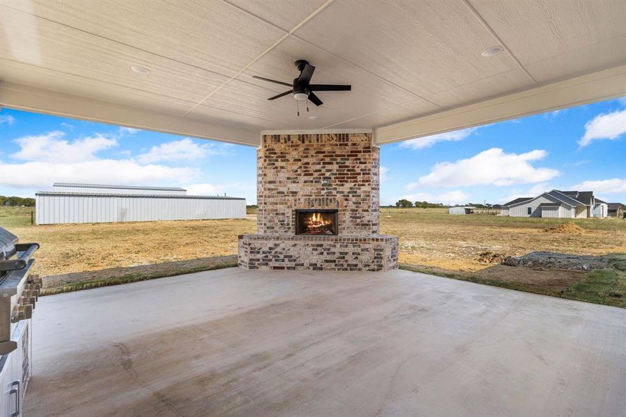 View of patio featuring an outdoor brick fireplace and ceiling fan