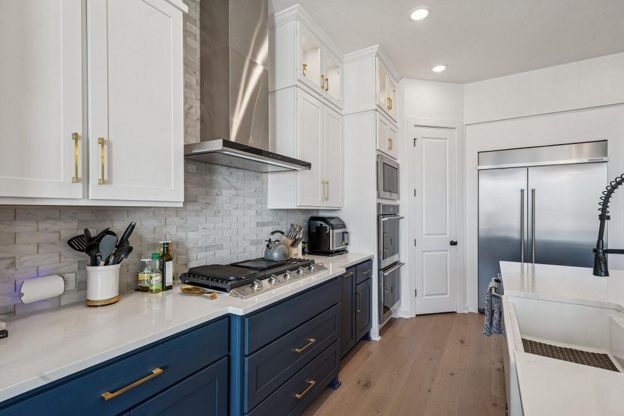 High-end appliances including heavy duty gas cooktop and high capacity hood framed by the marble backsplash all the way to the ceiling.
