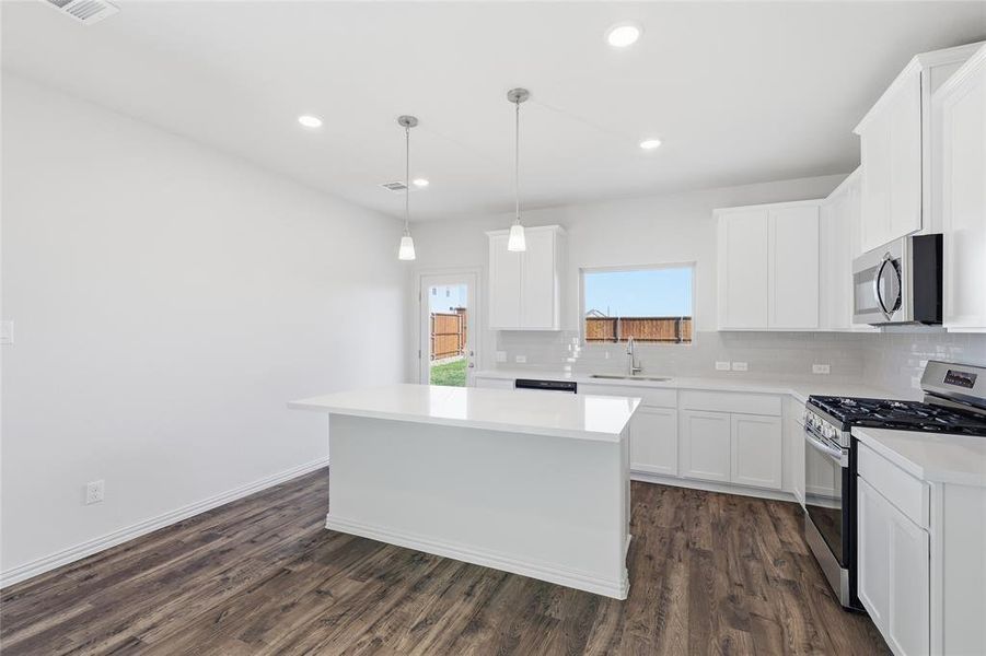 Contemporary kitchen featuring a bright white island, coordinating cabinetry, and stainless steel appliances