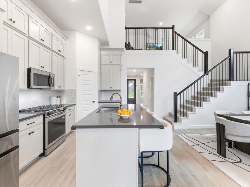 Striking view of the kitchen and dramatic stair case. Striking view of the kitchen and dramatic stair case.