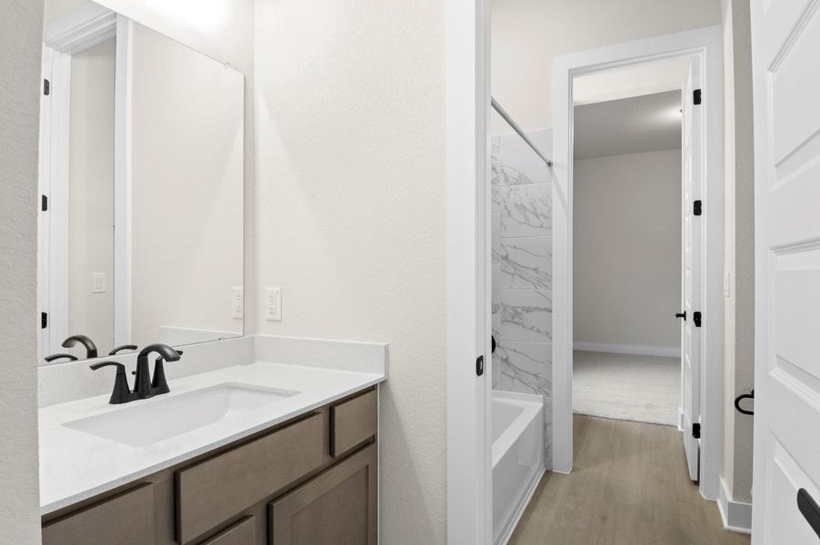 Bathroom featuring shower / washtub combination, vanity, and light wood-style floors