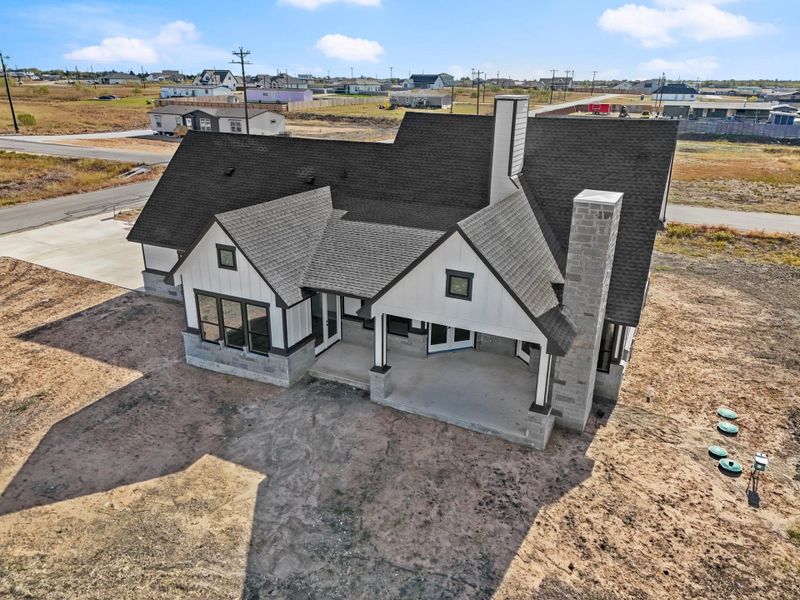 A newly constructed modern farmhouse with prominent gables and a stone-clad chimney stands ready for its landscape. A newly constructed modern farmhouse with prominent gables and a stone-clad chimney stands ready for its landscape.