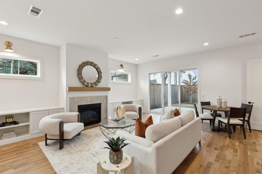 Living room featuring a fireplace, light wood-type flooring, and built in shelves