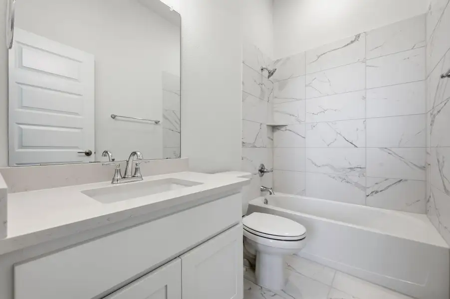 Bathroom featuring shower / tub combination, vanity, and light marble finish floors