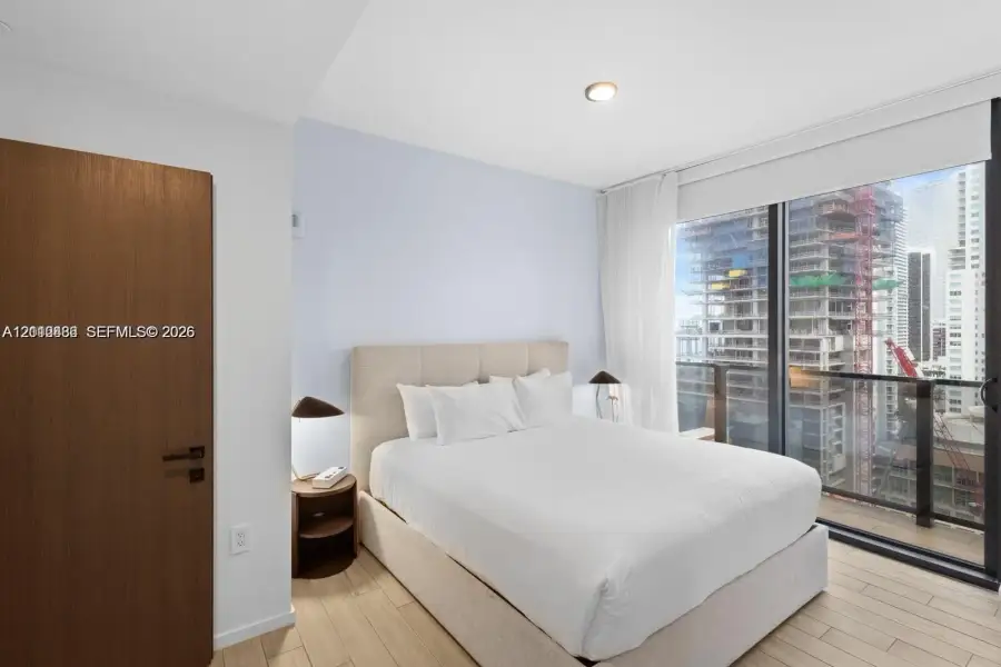 Floor-to-ceiling windows, wood-finish flooring, and a solid wood-finish door with matte black hardware Floor-to-ceiling windows, wood-finish flooring, and a solid wood-finish door with matte black hardware