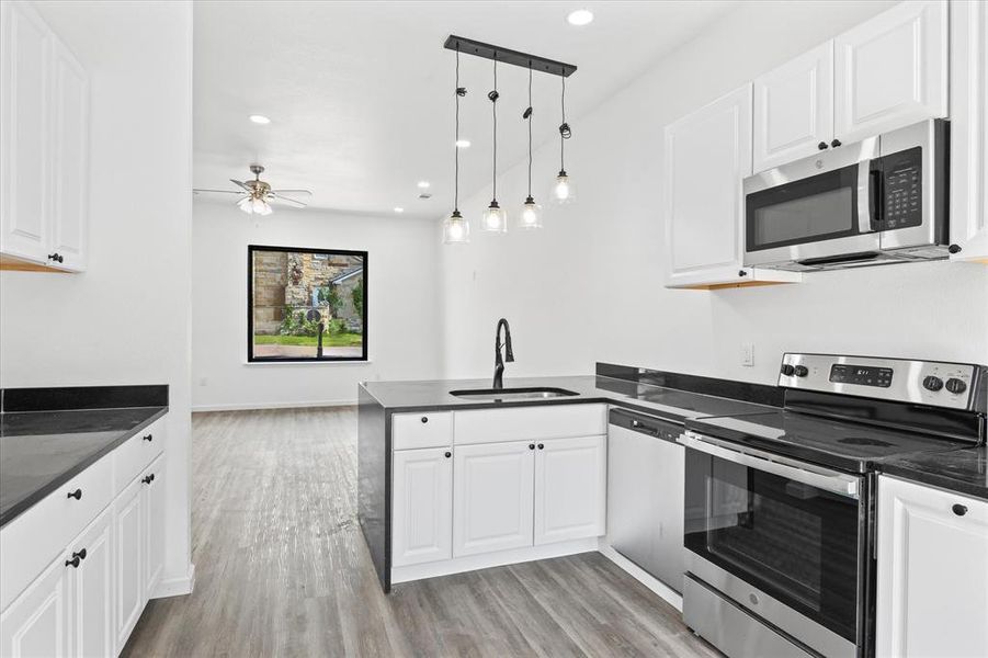 Kitchen featuring white cabinetry, kitchen peninsula, appliances with stainless steel finishes, and sink