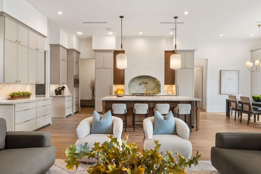 The chef’s kitchen features a large central island with substantial seating, custom cabinetry, and designer lighting. A statement arched backsplash and built-in range create a focal point, blending traditional craftsmanship with modern finishes.