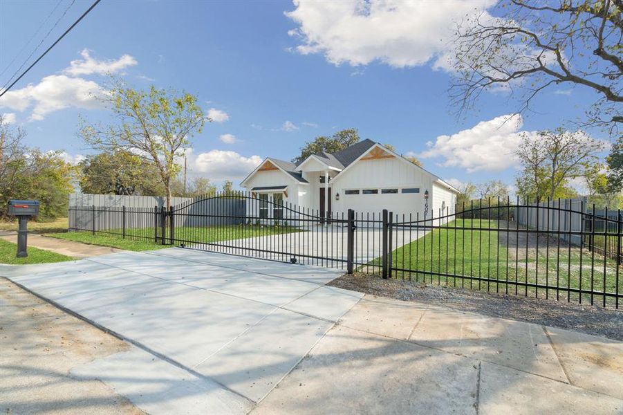View of front of property with driveway, a fenced front yard, a gate, and a garage