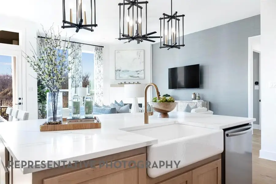 Kitchen featuring open floor plan, light stone counters, pendant lighting, and dishwasher