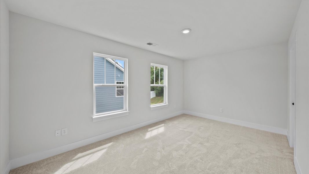 Highly functional bedroom with large windows, carpeted flooring, and tasteful finishes throughout