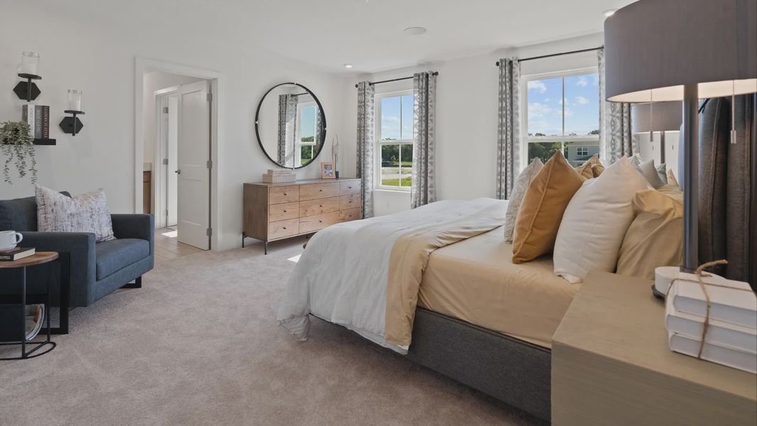 Carpeted primary suite with 2 large windows in a DRB Home Clementine model at the Trinity Place community.