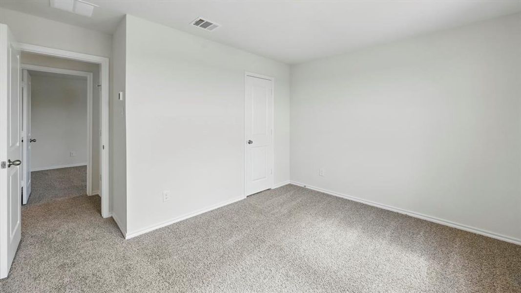 Unfurnished bedroom with light colored carpet and baseboards