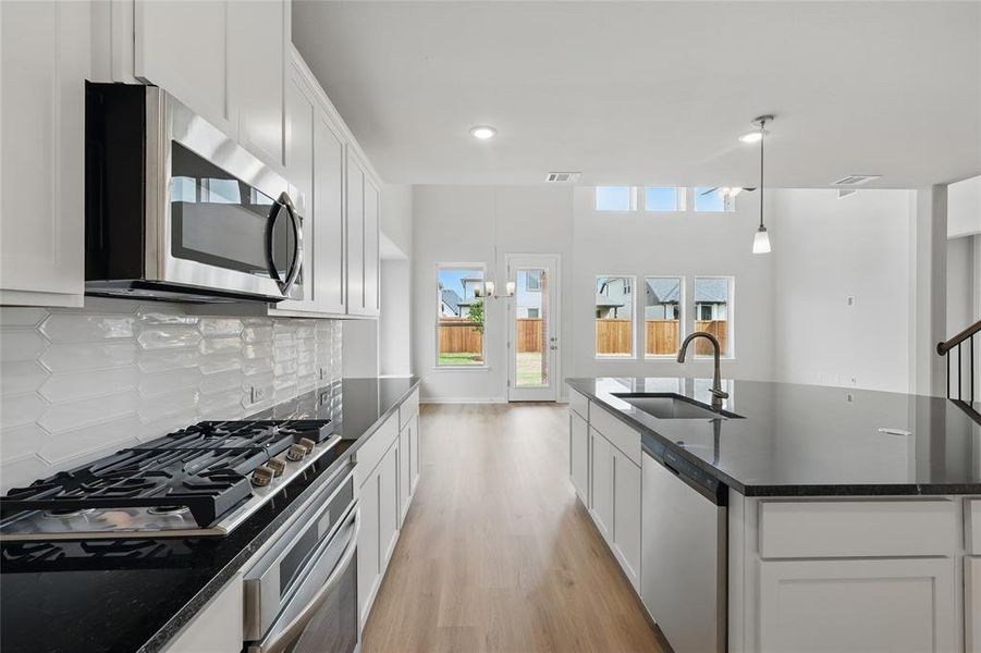 Kitchen featuring decorative backsplash, light wood-style floors, appliances with stainless steel finishes, a sink, and visible vents Kitchen featuring decorative backsplash, light wood-style floors, appliances with stainless steel finishes, a sink, and visible vents