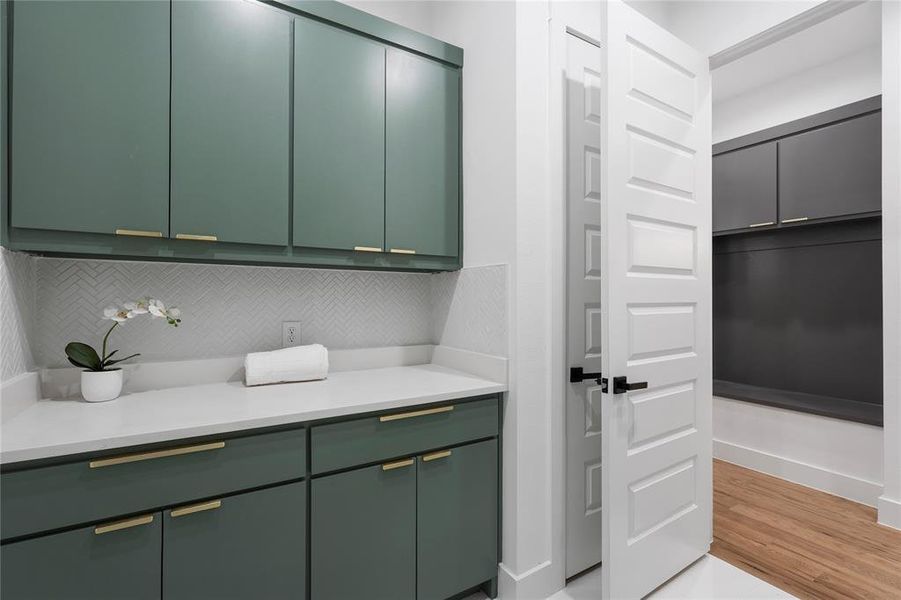 Kitchen with green cabinets, light countertops, and decorative backsplash