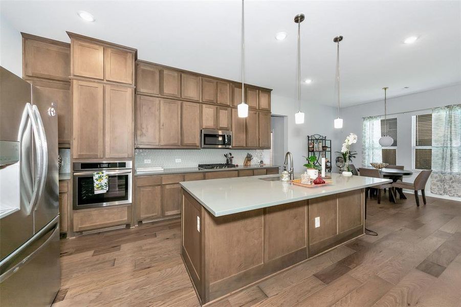 Kitchen with stainless steel appliances, pendant lighting, and a kitchen island with sink