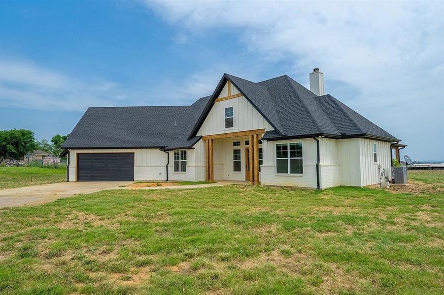 Modern inspired farmhouse featuring a chimney, central AC unit, a garage, concrete driveway, and a shingled roof