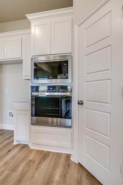 Kitchen featuring white cabinets, stainless steel appliances, and light hardwood / wood-style flooring