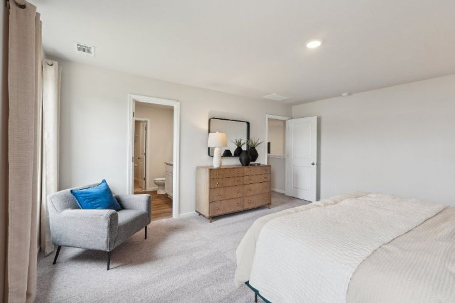 A bedroom with a bed and a chair.