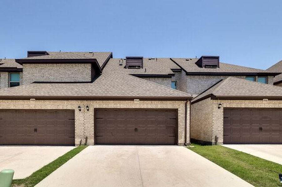 View of property with concrete driveway and a shingled roof