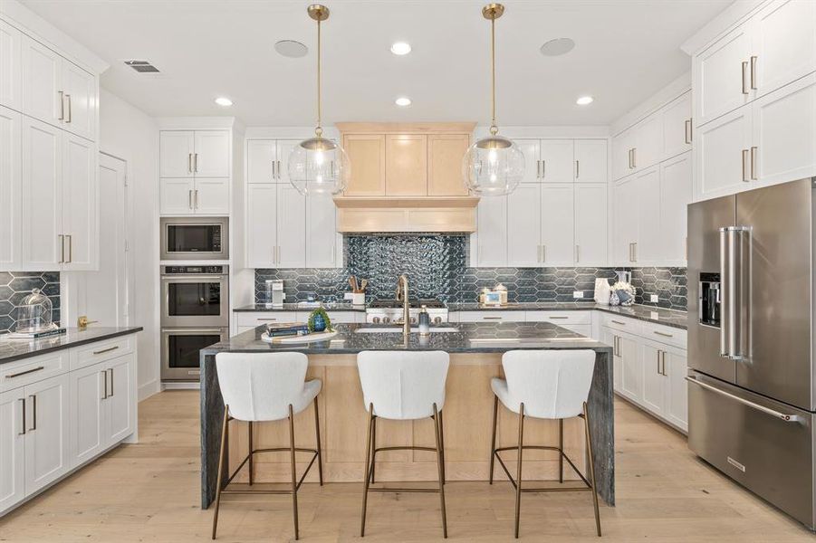 Kitchen featuring stainless steel appliances, tasteful backsplash, dark stone counters, light wood-style floors, and recessed lighting Kitchen featuring stainless steel appliances, tasteful backsplash, dark stone counters, light wood-style floors, and recessed lighting