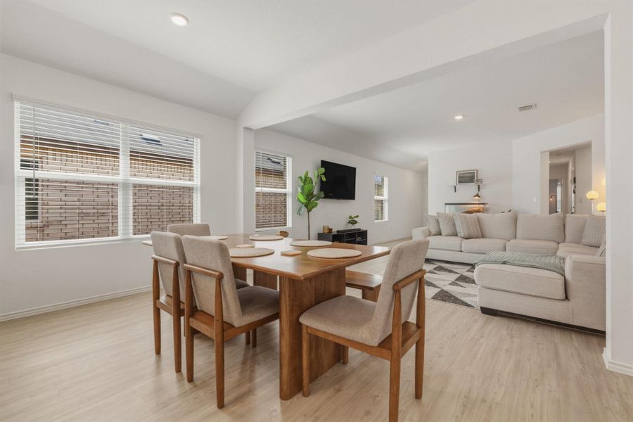 This bright dining area features light-colored flooring and large windows, providing natural light