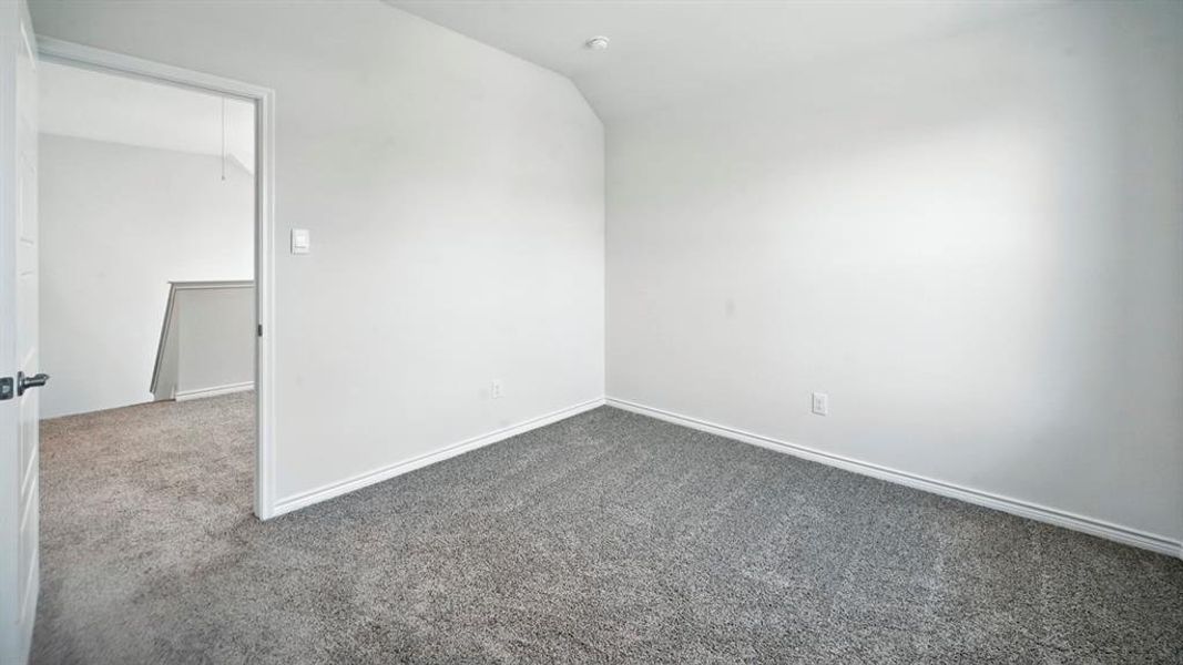 Spare room with vaulted ceiling and carpet