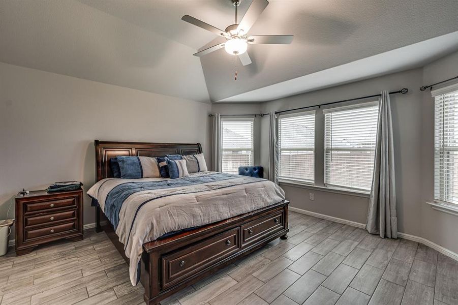 Bedroom featuring ceiling fan, vaulted ceiling, and light wood-type flooring