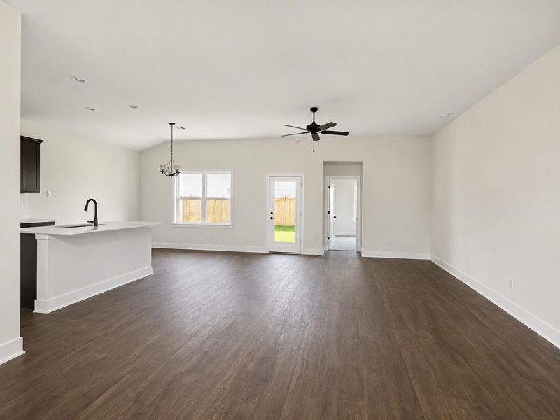 Open concept kitchen, dining, and living area featuring a large island with seating. AI decorated