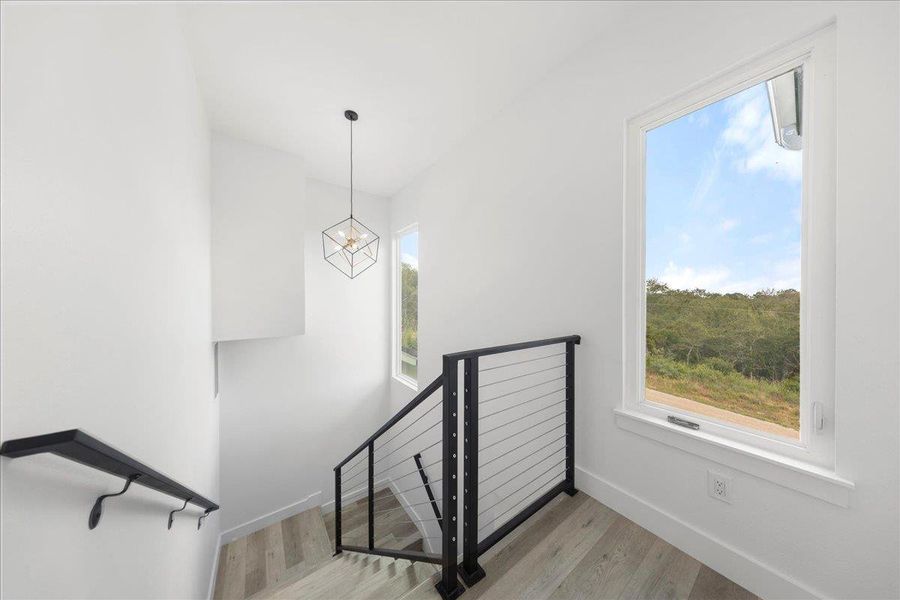 Staircase featuring wood finished floors, plenty of natural light, and a chandelier Staircase featuring wood finished floors, plenty of natural light, and a chandelier