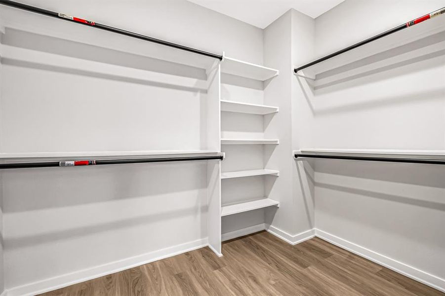 Large primary closet with plenty of hanging space and built in shelves.