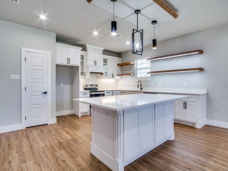 Kitchen with white cabinets, a center island, and light hardwood / wood-style flooring