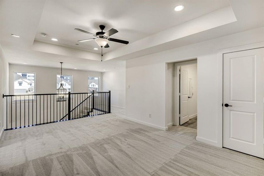 Carpeted spare room with a tray ceiling, ceiling fan, and recessed lighting