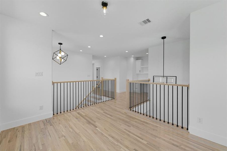 Empty room with light wood-style floors, recessed lighting, and a chandelier