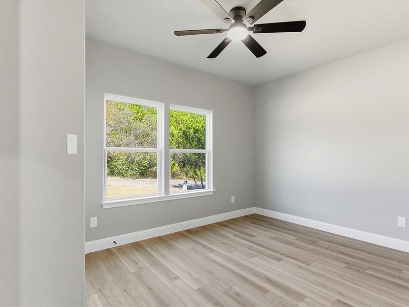 Empty room featuring light wood-style flooring and a ceiling fan Empty room featuring light wood-style flooring and a ceiling fan