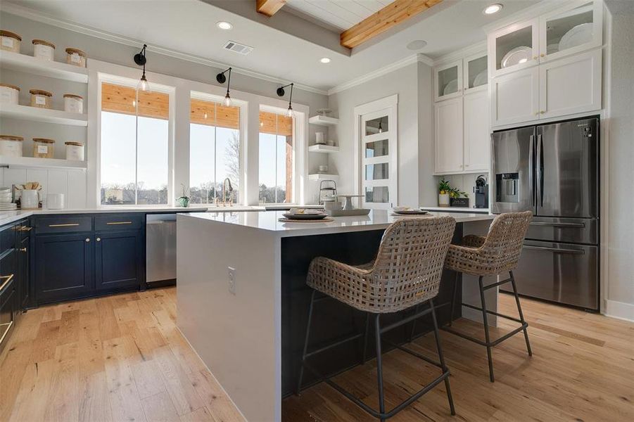 Kitchen featuring a center island, stainless steel appliances, a kitchen breakfast bar, blue cabinets, and white cabinets