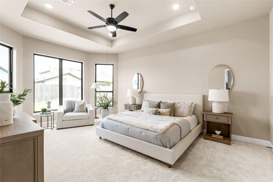 Welcome home to your sunlit primary bedroom featuring a tray ceiling, modern ceiling fan, and large windows overlooking the backyard. *Virtually Staged*