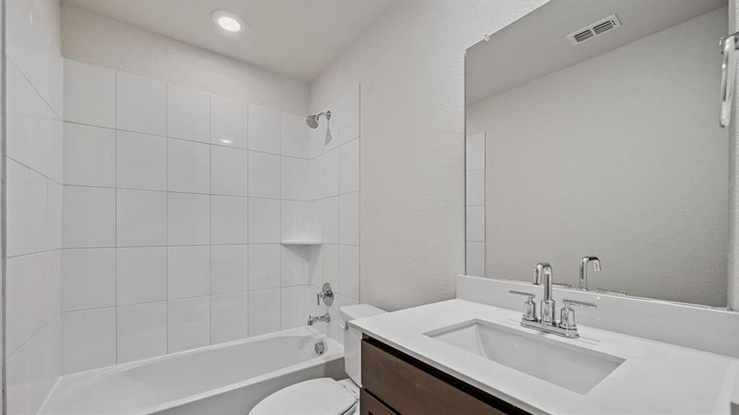 Bathroom featuring a tub/shower combination with white subway tile surround, a built-in shelf, and chrome fixtures Bathroom featuring a tub/shower combination with white subway tile surround, a built-in shelf, and chrome fixtures