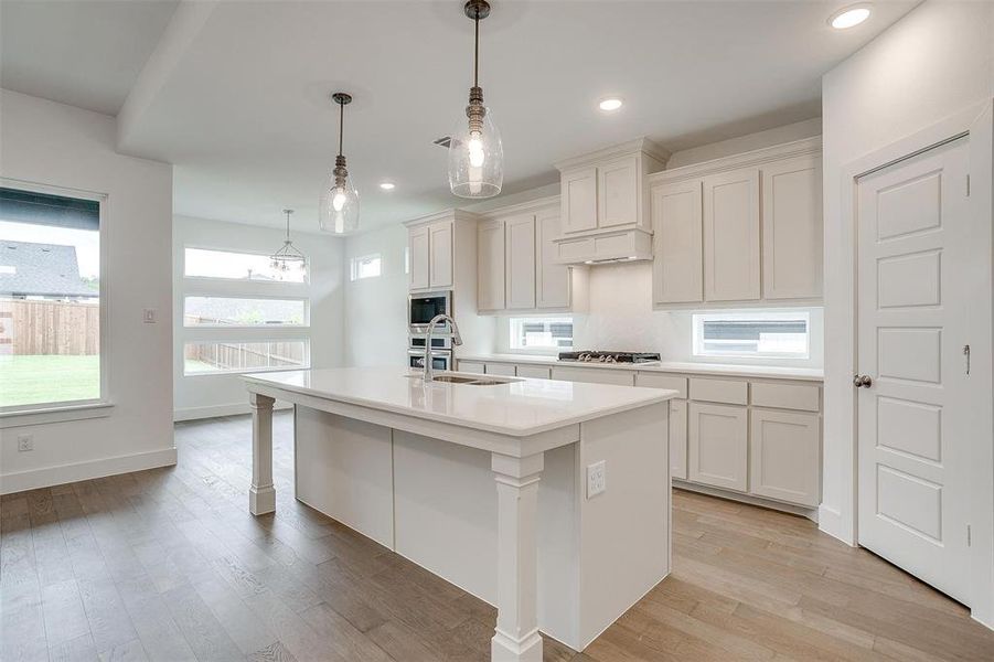 Kitchen with an island with sink, stainless steel appliances, light wood-type flooring, and sink