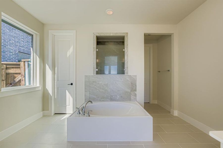 Full bathroom with a shower stall, a bath, and light tile patterned floors Full bathroom with a shower stall, a bath, and light tile patterned floors