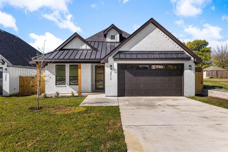 Modern farmhouse featuring a garage and a front lawn