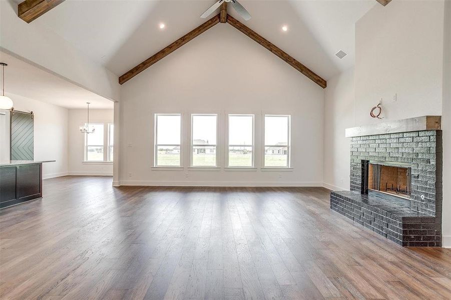 Unfurnished living room with high vaulted ceiling, hardwood / wood-style floors, and beam ceiling