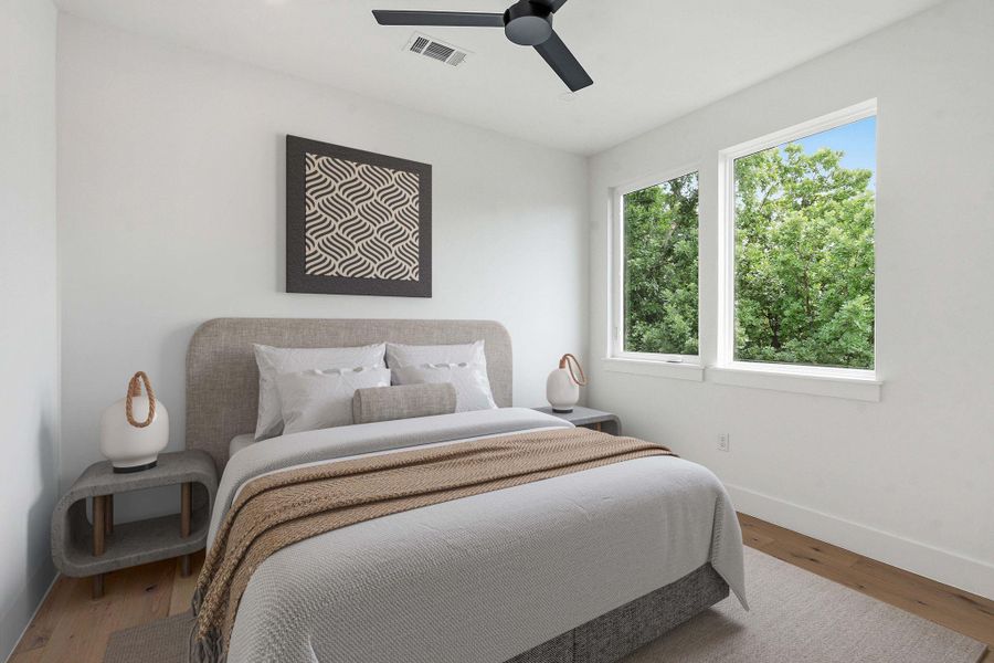 Light-filled room featuring two large windows, a ceiling fan, and wood-finish flooring
