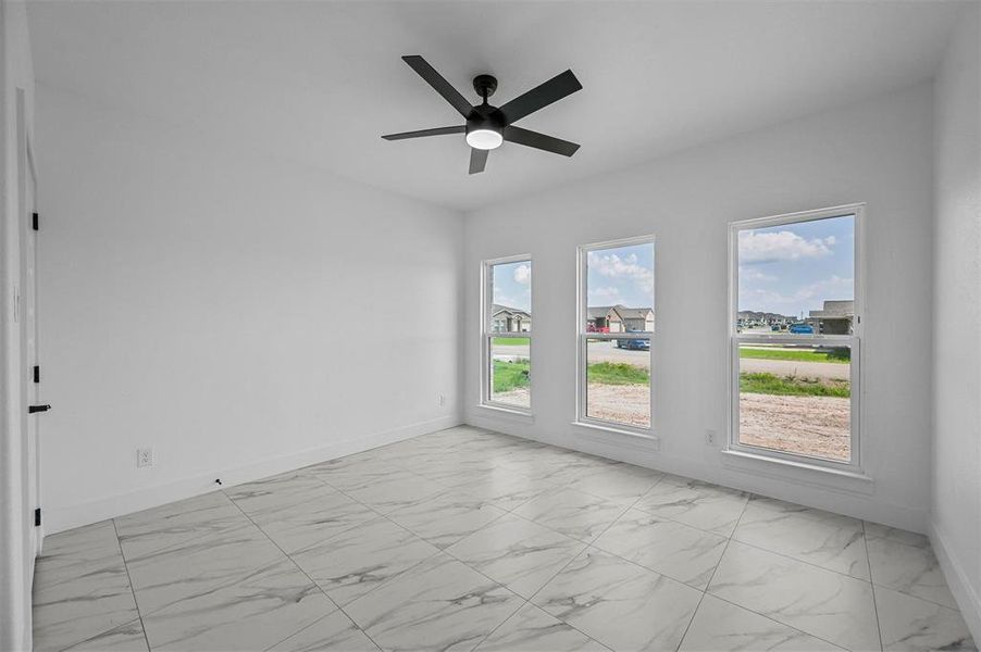 Tiled spare room featuring ceiling fan