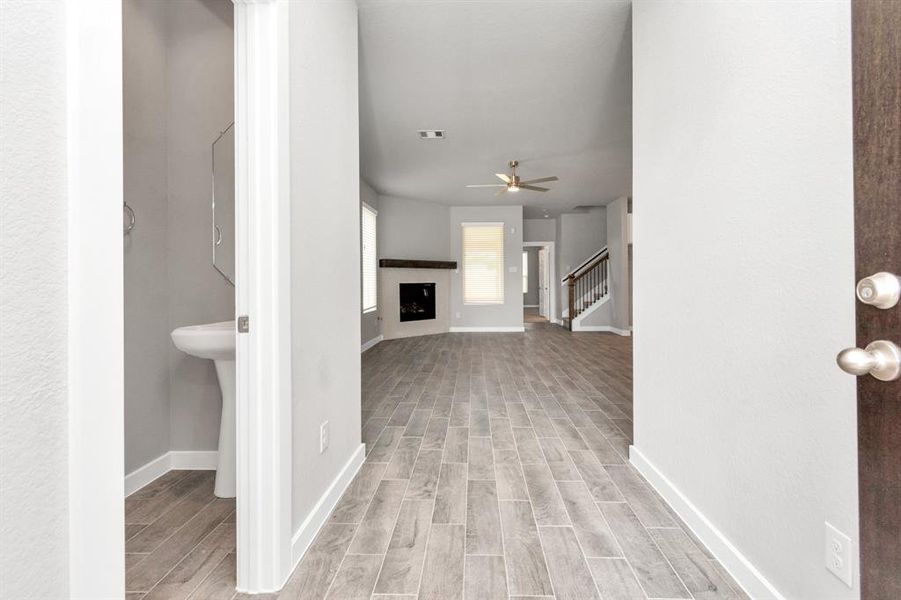 Greeted by an elegant glass front door, the entrance beckons with high ceilings, adorned with sleek wood-look tile flooring and oversized baseboards. Sample photo of completed home with similar floor plan. As-built interior colors and selections may vary.