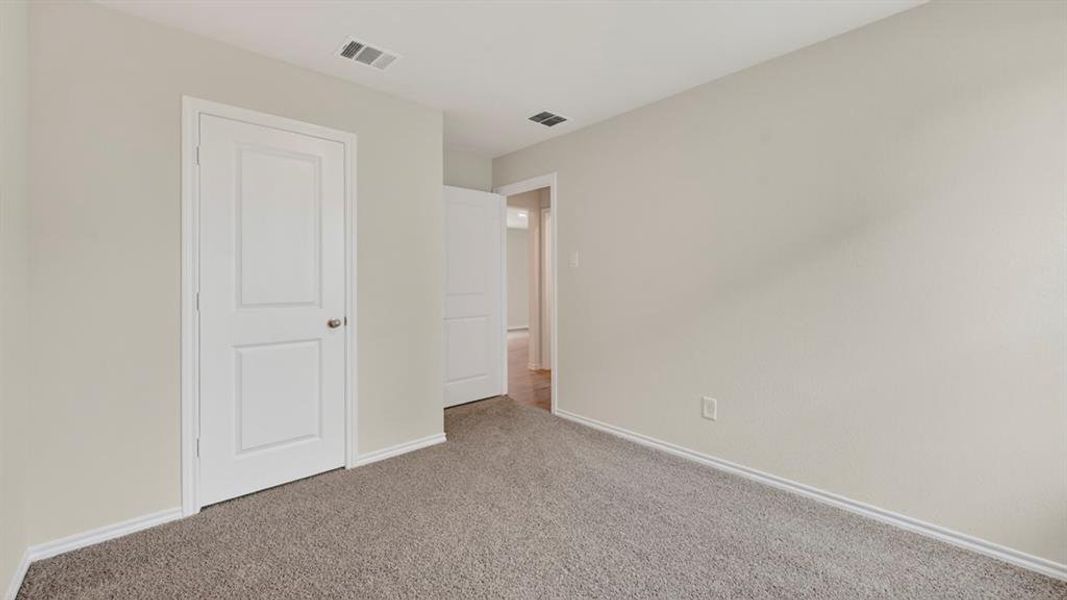 Neutral-toned room featuring a white paneled door, light gray walls, and gray carpet flooring