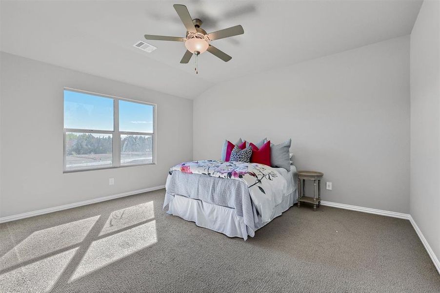 Carpeted bedroom with ceiling fan and lofted ceiling