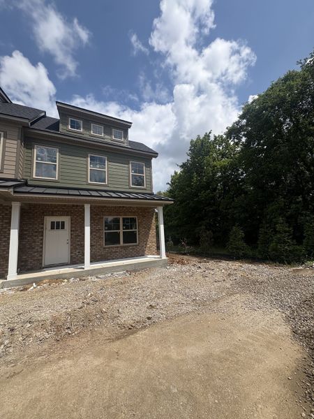 As of July 8, 2026, the current progress is as pictured. The house is situated on a corner lot, surrounded by lush greenery and a tree line.
