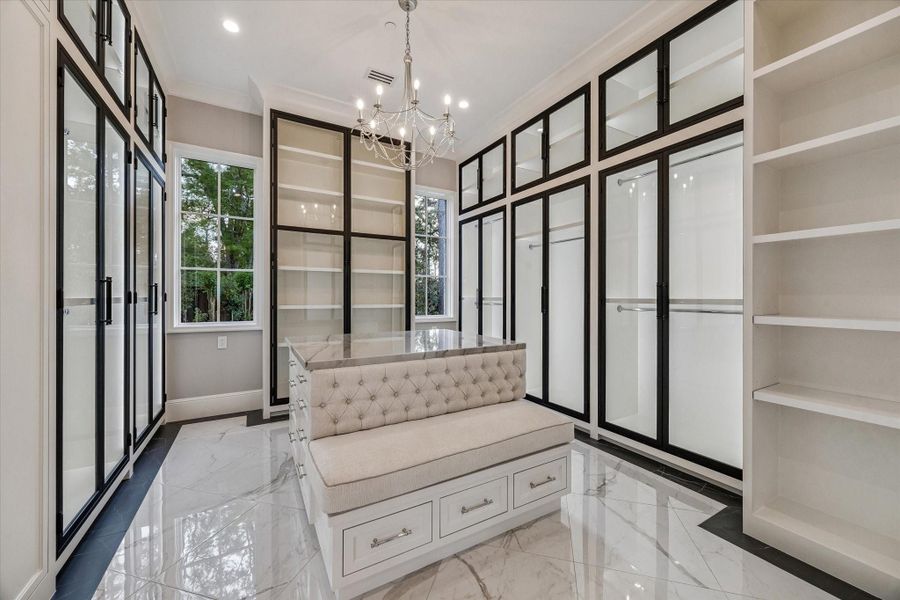 HER PRIMARY CLOSET WITH PACKING ISLAND, VANITY, AND UPHOLSTERED BENCH