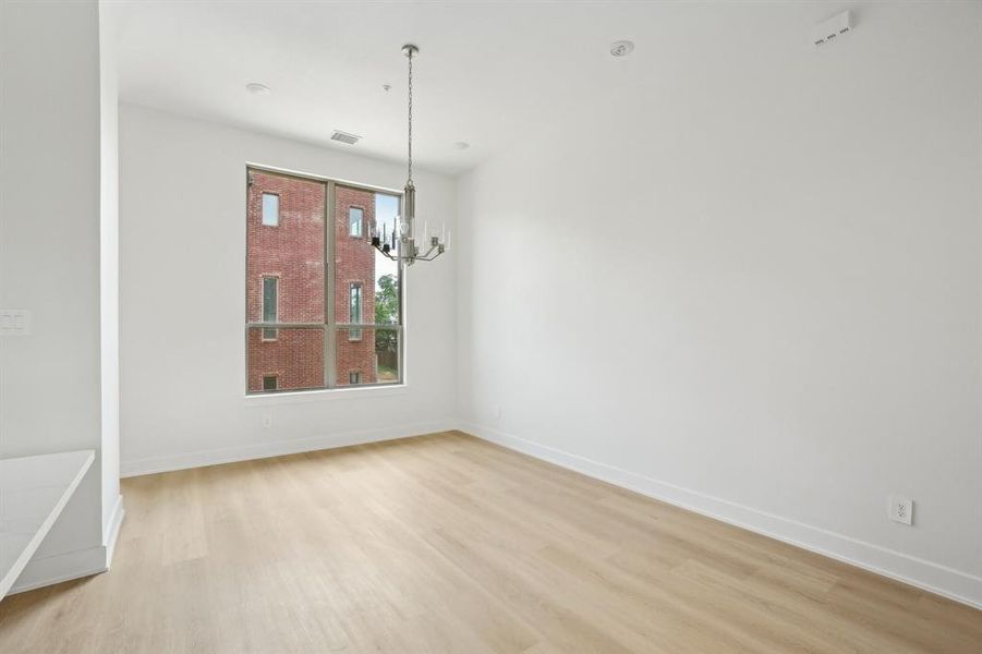 Unfurnished dining area with light wood finished floors, a chandelier, and baseboards