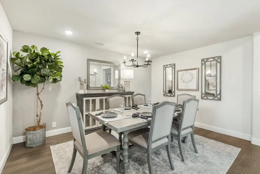 Dining room with six-chair gray table, chandelier, hardwood floors, and buffet cabinet against the wall.